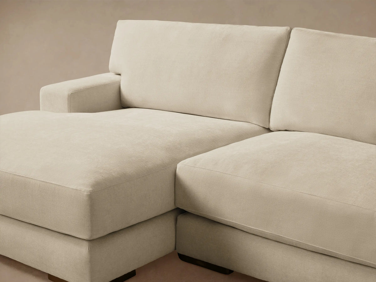 Norwalk Two-Piece Chaise Sectional in a light beige color, featuring a left-facing chaise and three-seater couch on a wooden floor.