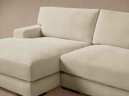 Norwalk Two-Piece Chaise Sectional in a light beige color, featuring a left-facing chaise and three-seater couch on a wooden floor.