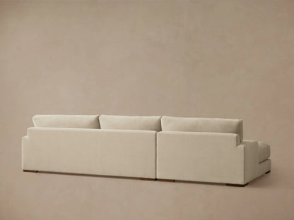A beige Norwalk Two-Piece Chaise Sectional with a left-side armrest and plush cushioning. The sectional sits on small wooden legs.