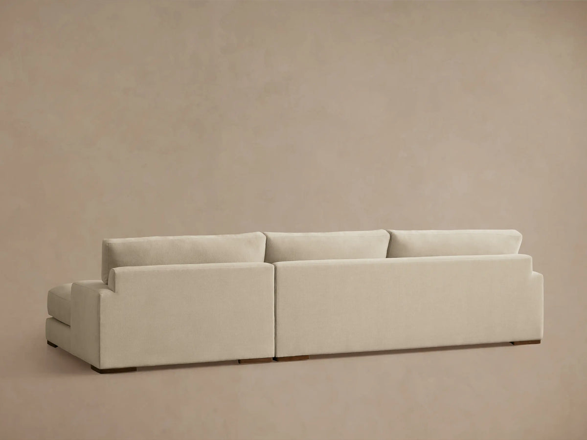 Norwalk Two-Piece Chaise Sectional in a light beige fabric, showing left-arm facing chaise with plush cushions and a solid base.