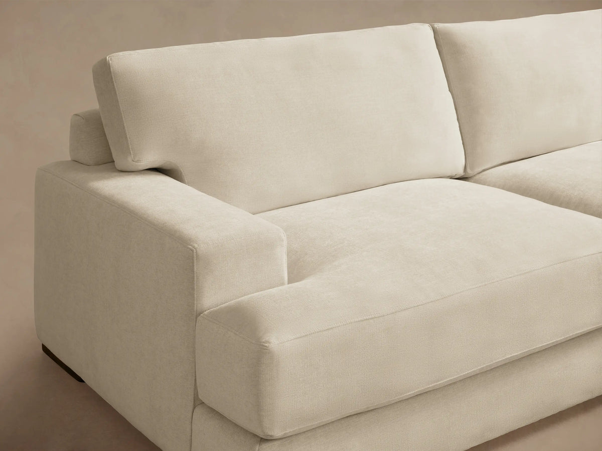 Norwalk Three-Piece Corner Sectional in beige fabric on wooden floor, featuring plush cushions and clean lines, forming an L-shape.