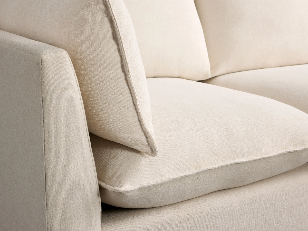 Owen Three Piece Modular Sofa in soft cream fabric, featuring plush cushions and clean lines on a hardwood floor.