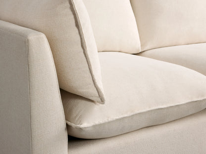 Owen Three Piece Modular Sofa in soft cream fabric, featuring plush cushions and clean lines on a hardwood floor.