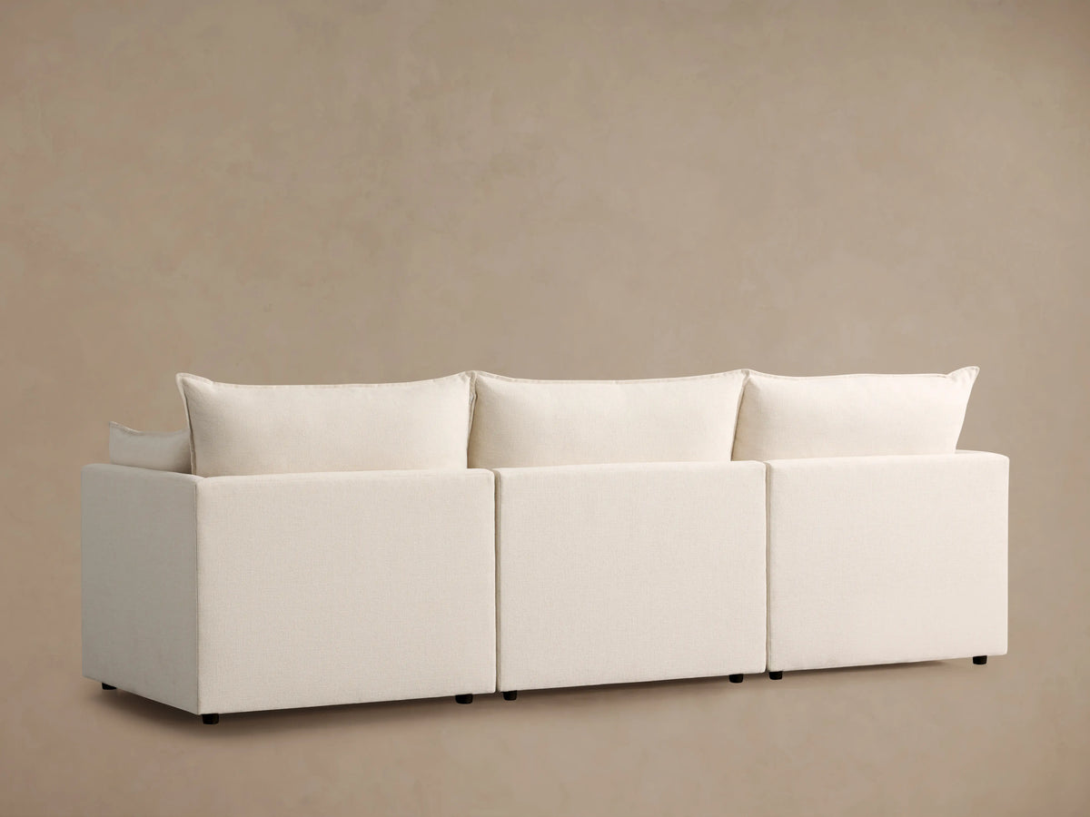 Close-up of the Owen Three Piece Modular Sofa showing plush cream cushions and soft, textured fabric, highlighting the padded armrest.