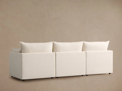 Close-up of the Owen Three Piece Modular Sofa showing plush cream cushions and soft, textured fabric, highlighting the padded armrest.