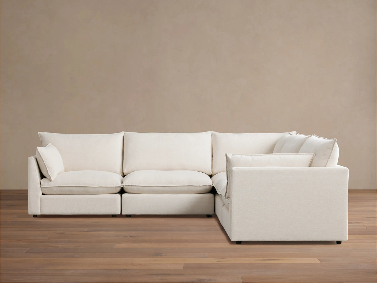 Owen Five-Piece Corner Sectional in cream fabric, featuring plush cushions and soft padding, arranged in an L-shape on wooden flooring.