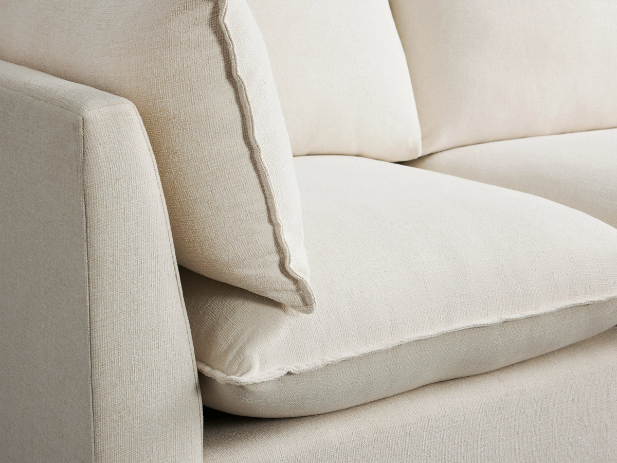 Owen Five-Piece Corner Sectional in off-white fabric, positioned in a spacious room with wooden flooring, featuring plush cushions and a modern design.