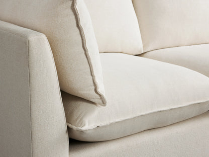 Owen Five-Piece Corner Sectional in off-white fabric, positioned in a spacious room with wooden flooring, featuring plush cushions and a modern design.