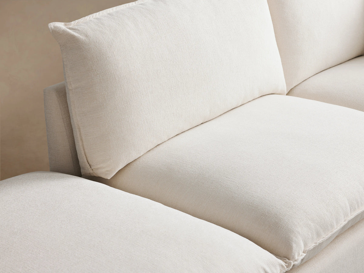 Owen Five-Piece Sectional in cream fabric on a wooden floor, featuring cushioned seats and backrests, arranged in an L-shape.