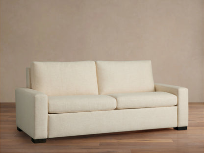 Front view of a cream Remington Luxury Sleeper Sofa with square arms, two seat cushions, and two back cushions, on a wood floor.