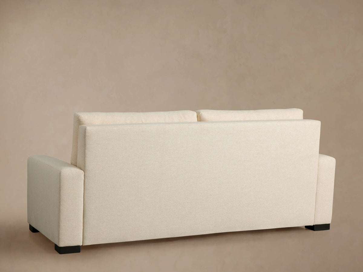 Close-up of Remington Luxury Sleeper Sofa's light beige textured woven fabric, showing back cushions & armrest.