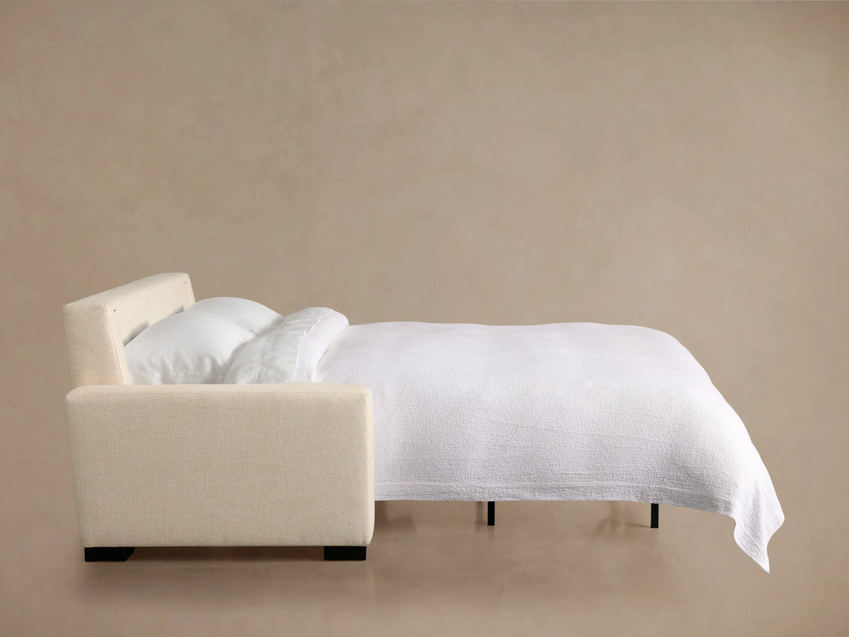 Beige Remington Luxury Sleeper Sofa unfolding, showing its white mattress and black pull-out mechanism.