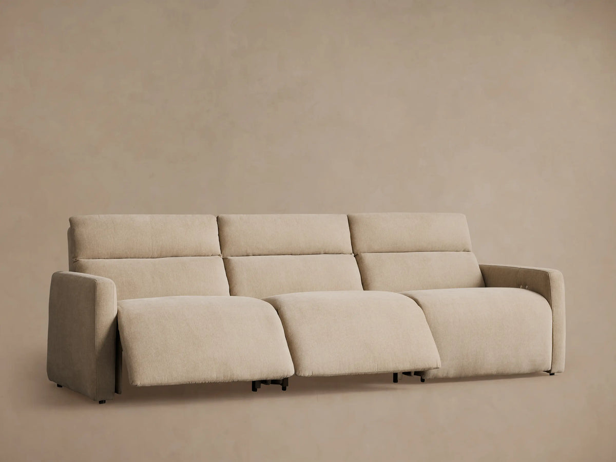 Close-up, high-angle view of a Rowland Three-Piece Modular Sofa in a light tan, woven fabric, showing plush cushions and an armrest.