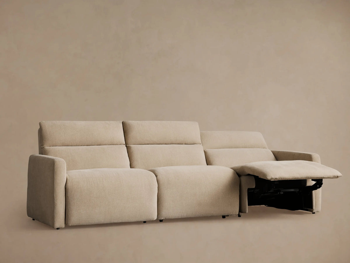 Light beige Rowland 3-piece motion modular sofa. Two sections recline with footrests extended, on a neutral backdrop.