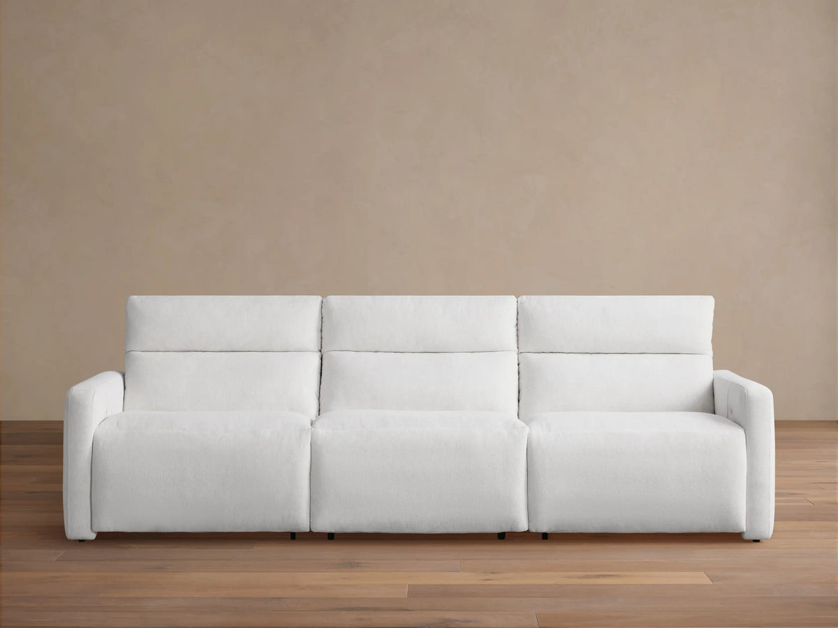 Front view of a white Rowland Tailored Three-Piece Motion Modular Sofa on a wood floor, against a beige wall. Plush, tailored fabric.