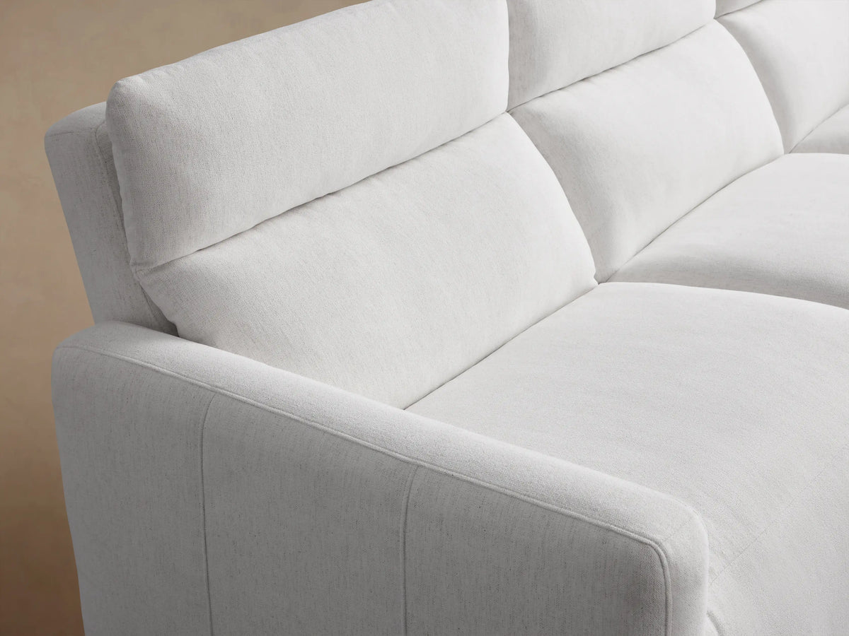 White Rowland Tailored Three-Piece Motion Modular Sofa, centered, against a warm beige wall on a light wood floor.