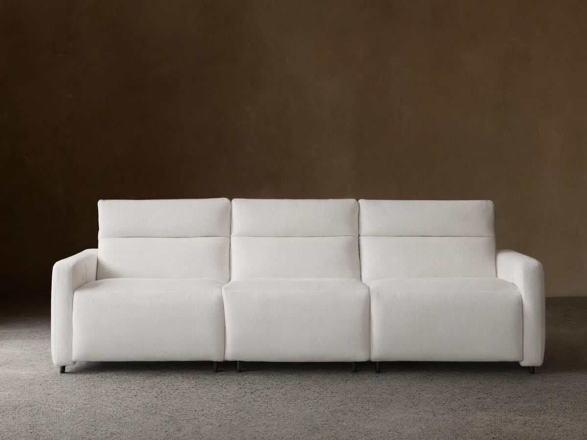 Front view of a white Rowland Tailored Three-Piece Motion Modular Sofa on a wood floor, against a beige wall. Plush, tailored fabric.