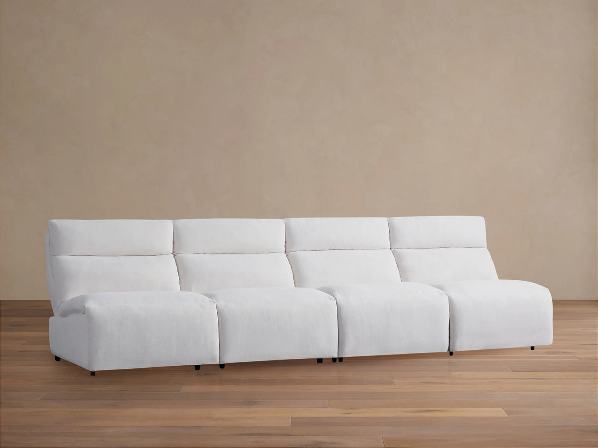 Rowland Tailored Four-Piece Armless Motion Modular Sofa in white, viewed straight-on on wooden floor against a beige wall.