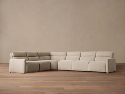 Rowland Tailored Six-Piece Motion Sectional, light beige fabric, L-shaped, on a hardwood floor against a muted tan wall.
