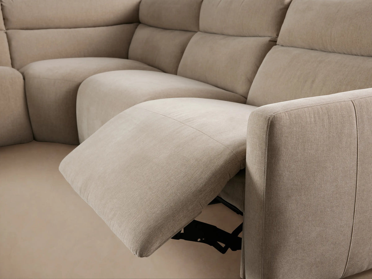 Rowland Tailored Six-Piece Motion Sectional, light beige L-shaped sofa on a wood floor against a tan wall.