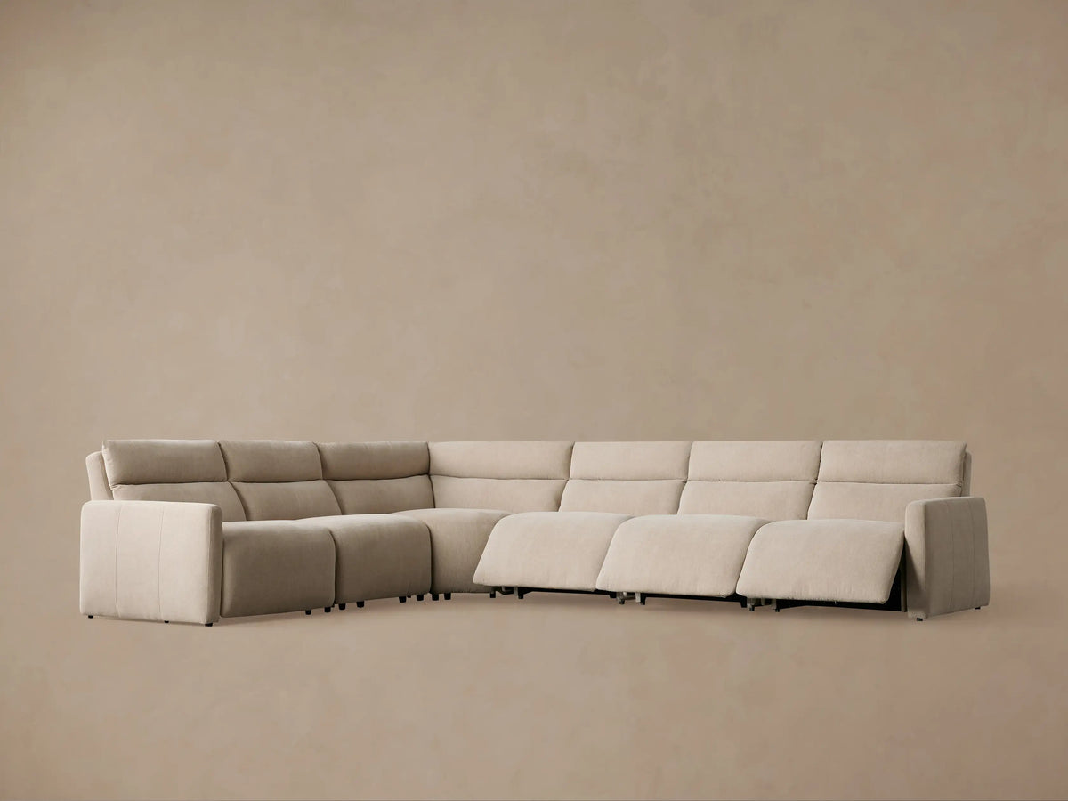 Close-up of Rowland Tailored Sectional in light beige, showing textured fabric on seat, armrest, and base with two silver buttons.