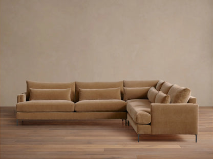 Sumner Three-Piece Corner Sectional in light brown fabric, featuring plush cushions and lumbar pillows, set on wood flooring.