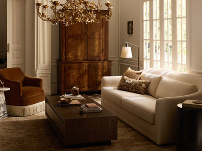A beige Bianca Sofa with curved armrests and two large seat cushions. Made from soft performance fabric, set against a light brown wall and wooden floor.