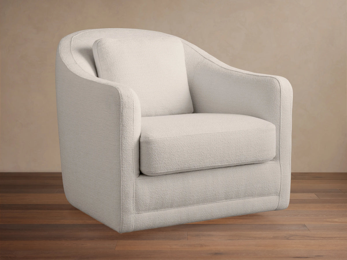 Off-white Bianca Swivel Chair in textured fabric, with rounded back & arms, separate seat & back cushions, on wood floor.