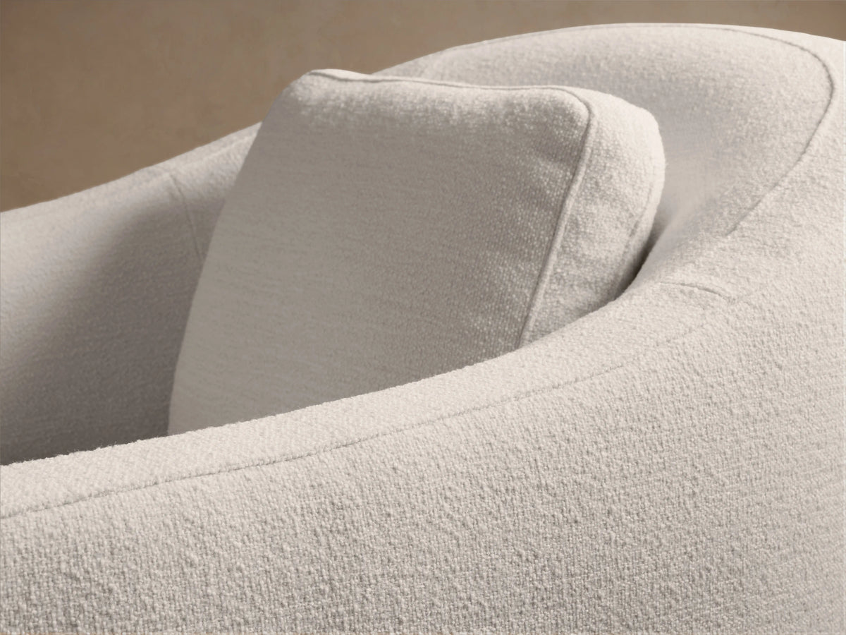 Light cream Bianca Swivel Chair, textured fabric, rounded back and arms, with a seat and back cushion. Front view on wood floor.