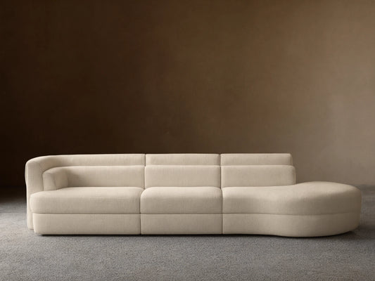 Lovina Three-Piece Bumper Sectional in cream textured fabric, with a rounded chaise left and armrest right, on a wooden floor.