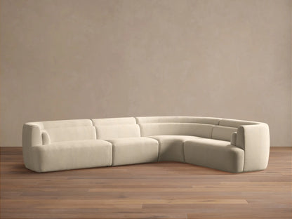 Off-white Lovina Four-Piece Sectional with deep seats, soft upholstery, and brown throw pillows, arranged in a sunlit living room.
