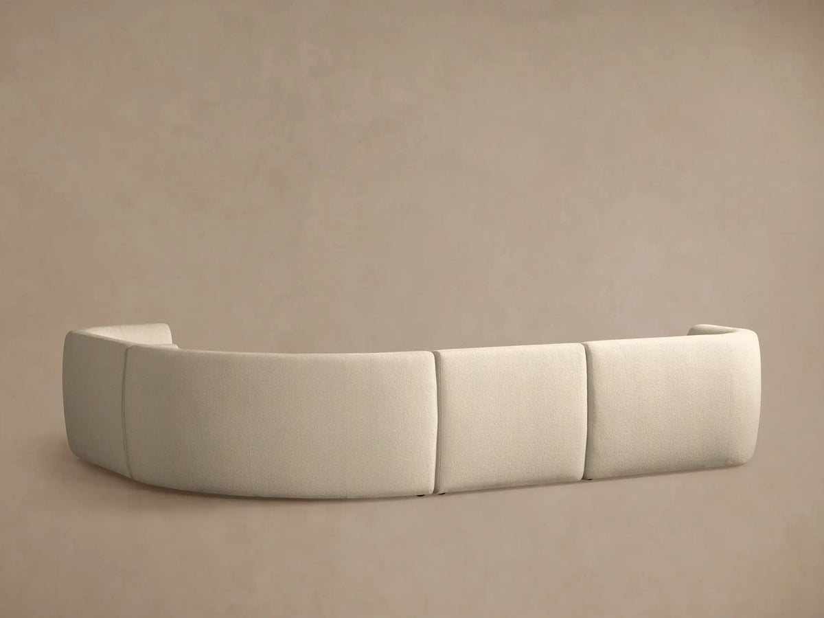 Close-up of curved Lovina Four-Piece Sectional. Light beige textured fabric, showing plush seat and back cushions.