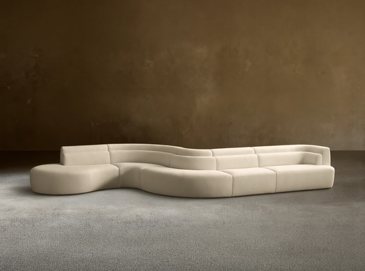 Light beige Lovina Five-Piece Sectional, a wavy, modular sofa with rounded chaise, on a wood floor against a beige wall.