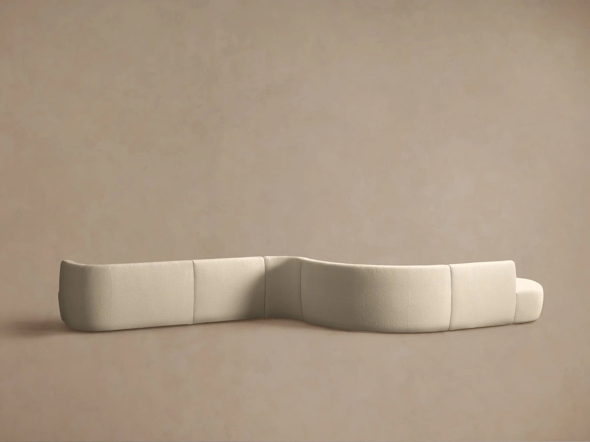 Close-up of Lovina Five-Piece Sectional showing its sculptural, curved backrest and seat in a soft, textured light beige fabric.