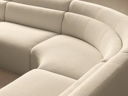 Lovina cream five-piece curved sectional sofa with ottoman on left, on a wooden floor against a neutral wall.