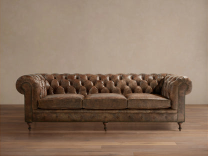 Full-length Wessex Leather Sofa with distressed brown tufted back, rolled arms, three seat cushions, nailhead trim, on wood floor.