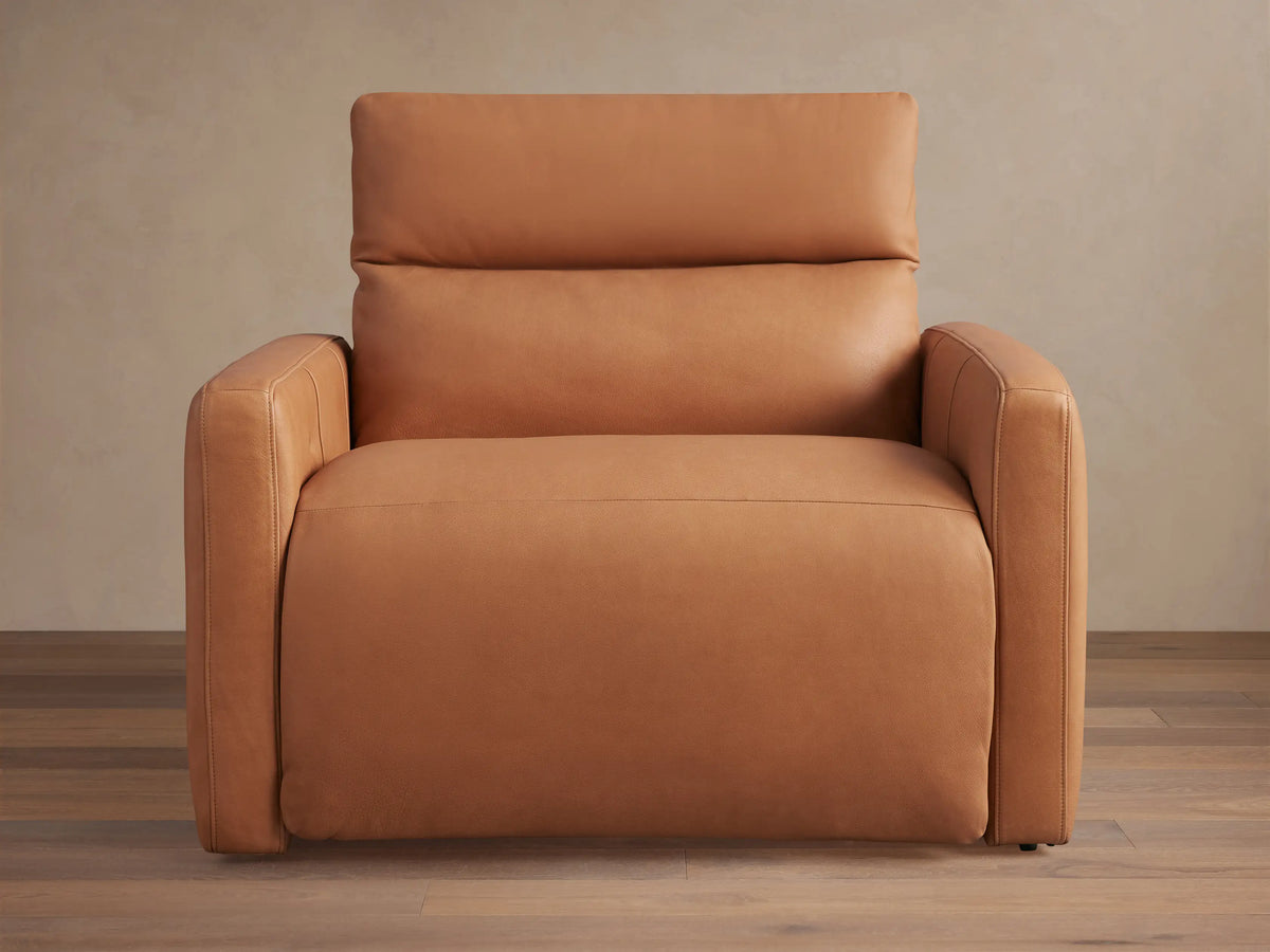 Rowland Tailored tan leather high-back motion recliner, front view, on a warm wooden floor against a neutral wall.