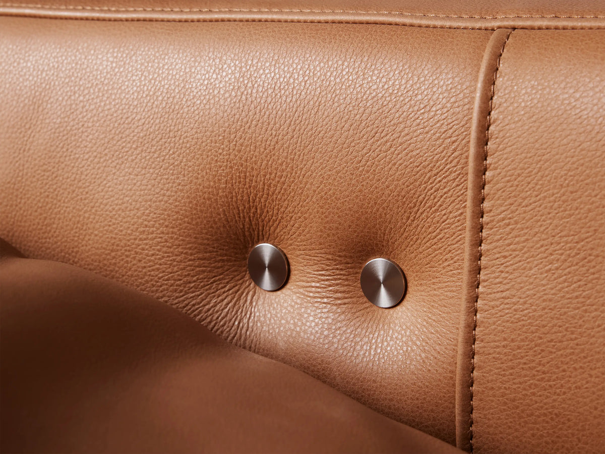 Close-up of the soft tan leather upholstery of a Rowland Tailored Motion Recliner, showing natural folds and fine grain texture.