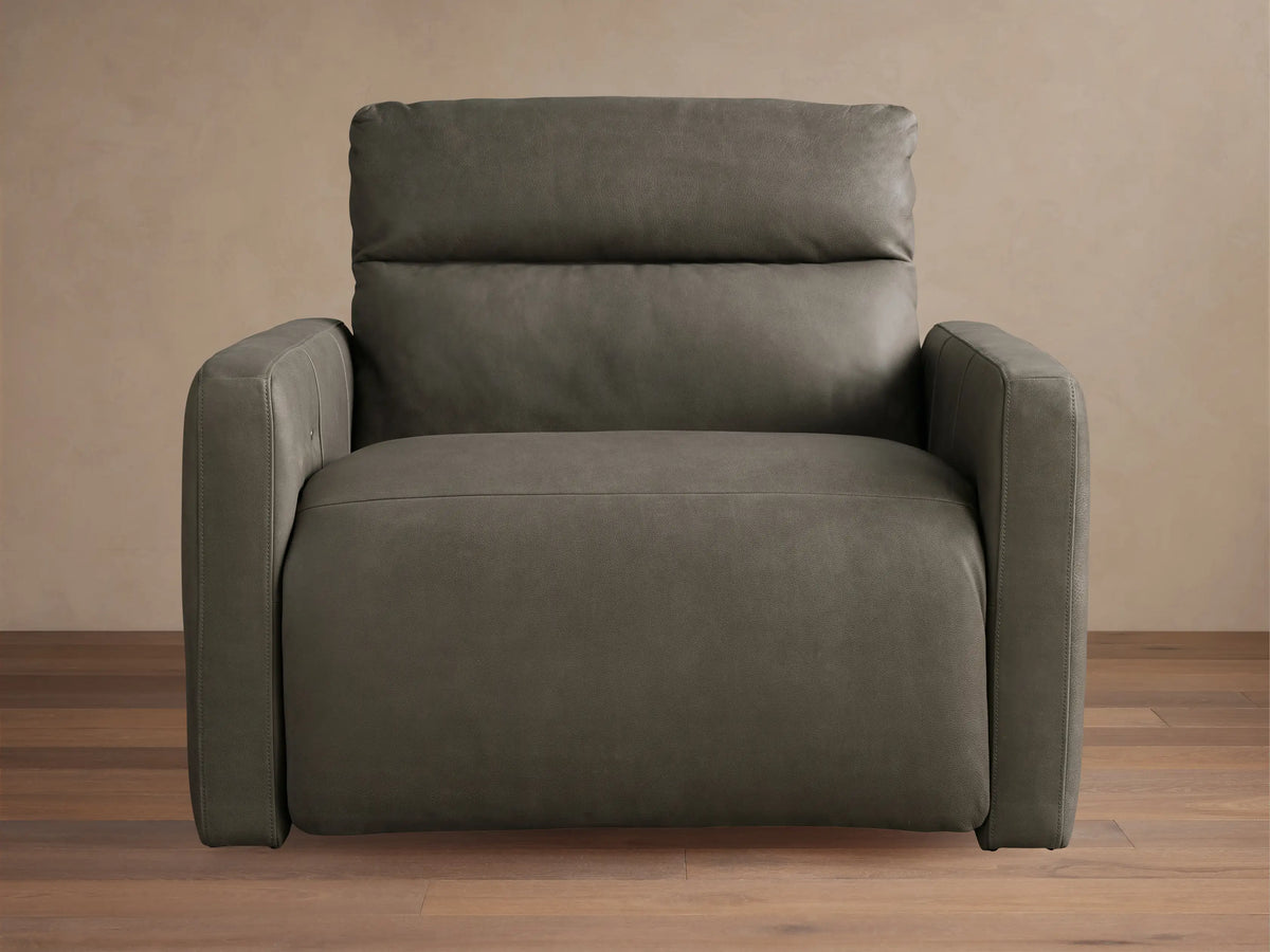 Rowland Tailored Leather High-Back Motion Recliner, charcoal grey, upright, plush cushions, on a wood floor.