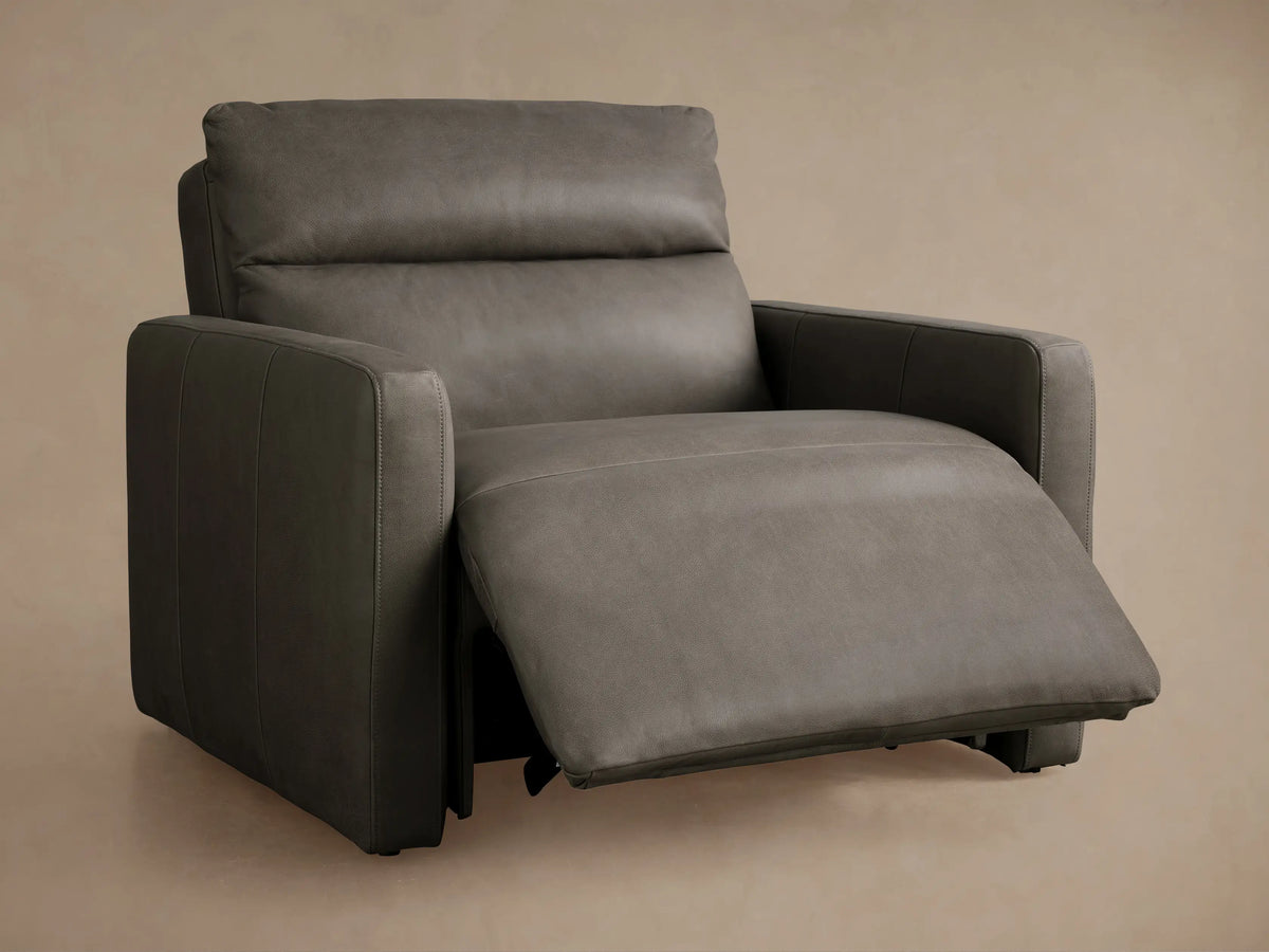 Rowland Tailored Leather Recliner: Close-up of textured grey leather with tufting, two shiny silver buttons, and vertical seam.