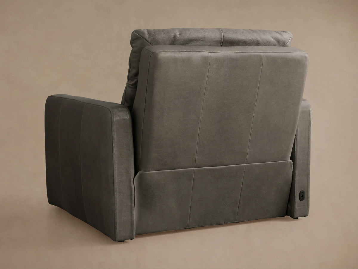 Dark gray Rowland Tailored Motion Recliner, side view, fully reclined with footrest extended against a beige wall.