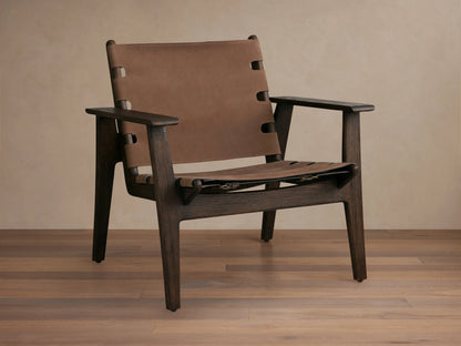 Nubuck leather chair with a sling-style seat, secured by antique brass buckles on a red oak frame, shown on wood floor.