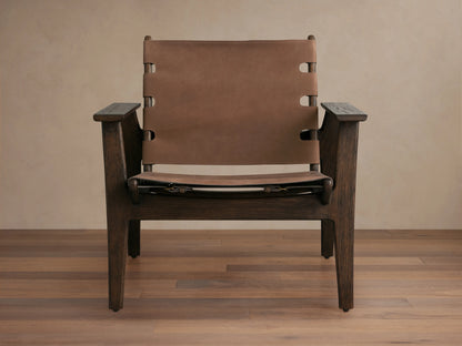 Nubuck leather chair with a sling-style seat, secured by antique brass buckles on a red oak frame, shown on wood floor.