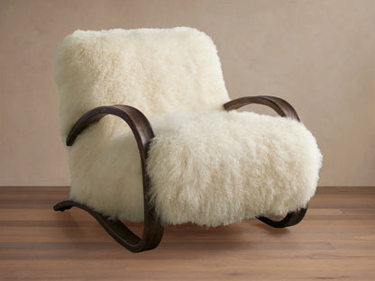 Allora Mongolian Shearling Chair. Creamy white fluffy shearling armchair with dark curved wood frame on a wooden floor.