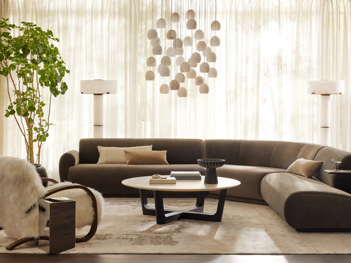 Allora Mongolian Shearling Chair. Creamy white fluffy shearling armchair with dark curved wood frame on a wooden floor.