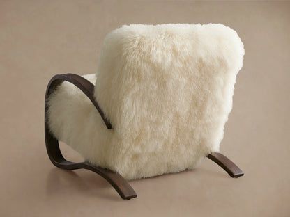Allora Mongolian Shearling Chair: Close-up of a cozy cream shearling chair with curved dark mocha wood arms and base frame.