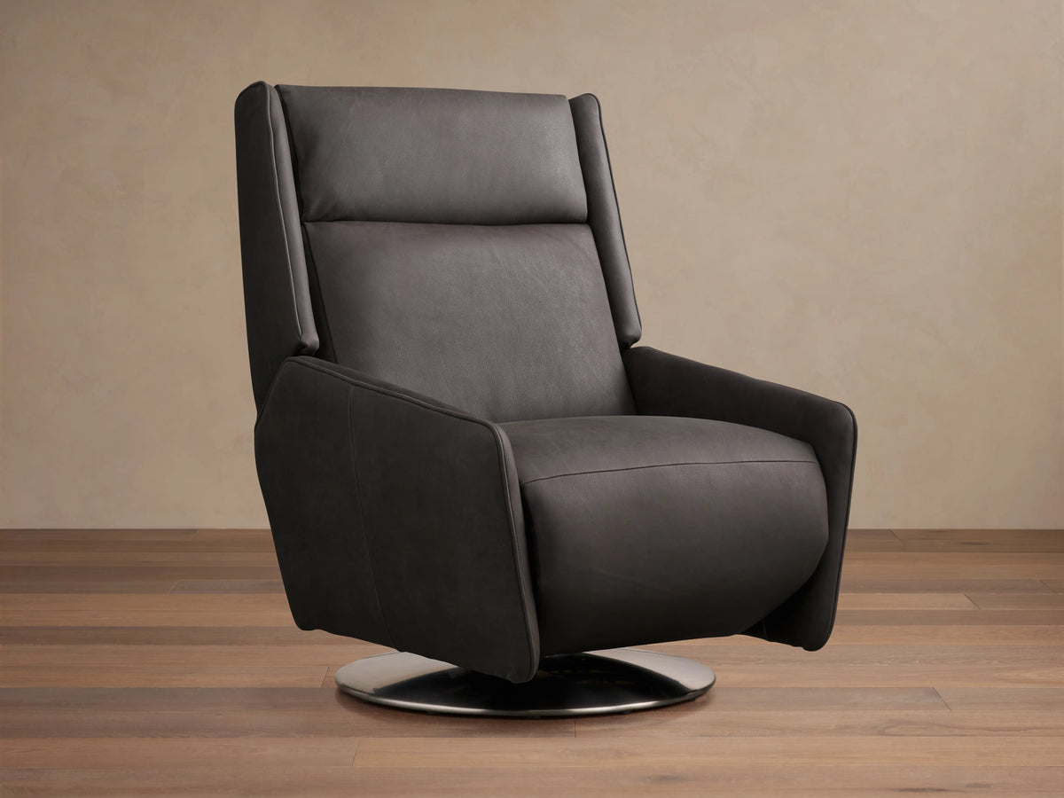 Dark leather Hurley Motion Swivel Chair on wooden floor, featuring sleek lines, high backrest, and metal swivel base in a neutral room.