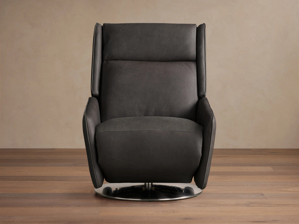 Dark leather Hurley Motion Swivel Chair on wooden floor, featuring sleek lines, high backrest, and metal swivel base in a neutral room.