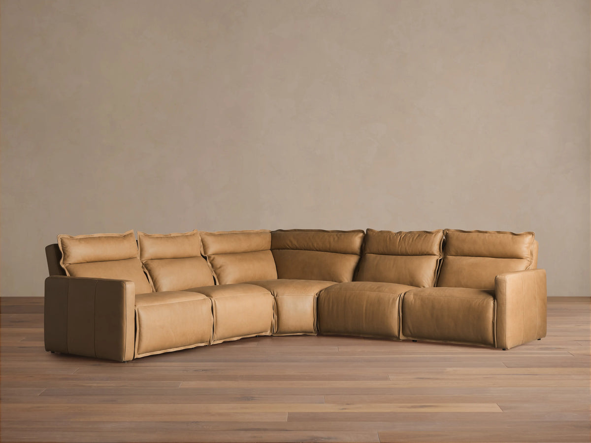 Tan Rowland Leather Five-Piece Motion Corner Sectional on wood floor, showcasing plush backrests and cushioned seats in an L-shaped layout.
