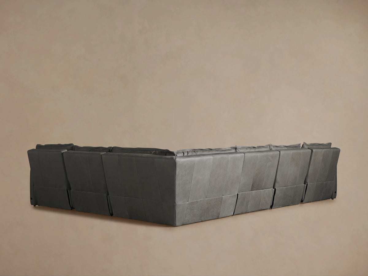 Rowland Leather Six-Piece Motion Sectional in dark leather, arranged in an L-shape, on a wooden floor with a beige wall background.